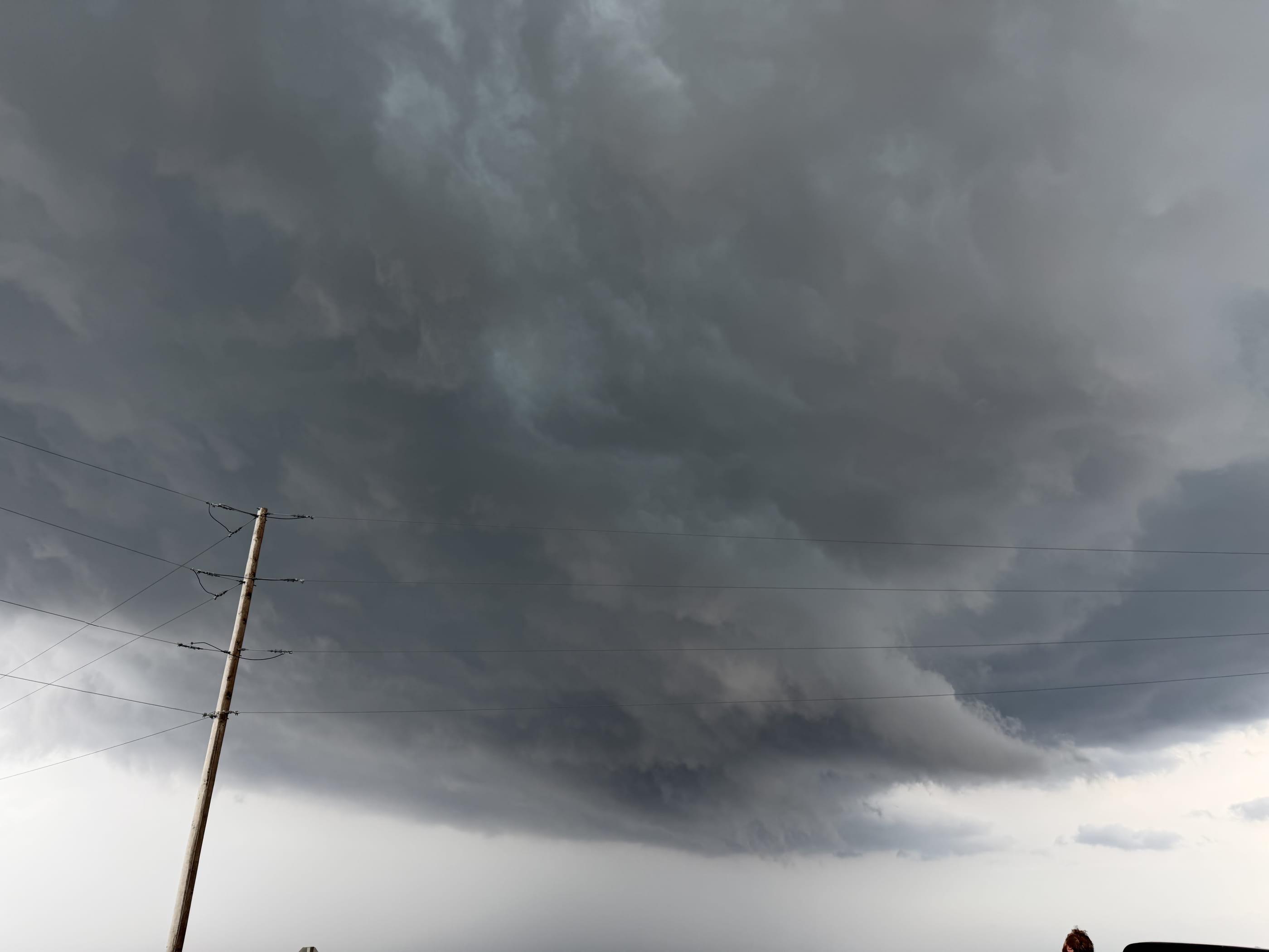 A low, banded storm base filling the sky above a utility pole and power lines.